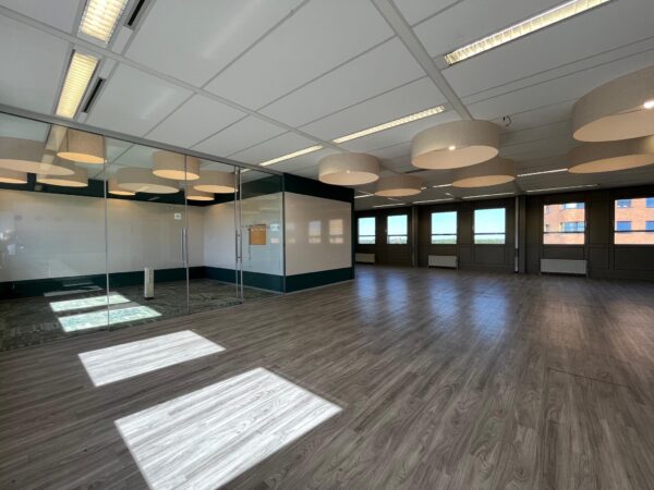 Lichte, moderne kantoorruimte aan de Barchman Wuytierslaan met glazen vergaderruimte en houten vloer.